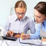 Dos profesionales revisan documentos contables y calculan beneficios tributarios por donaciones a proyectos de reforestación en Colombia