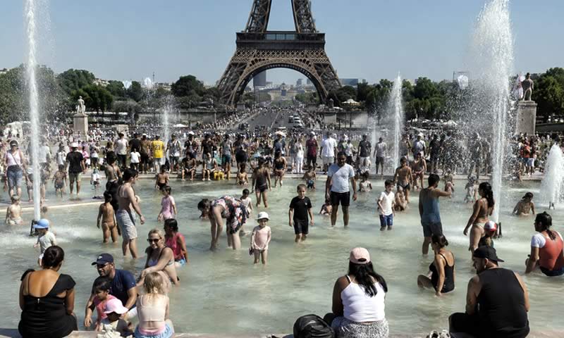Personas refrescándose en las fuentes del Trocadéro frente a la Torre Eiffel durante una intensa ola de calor en París, Francia
